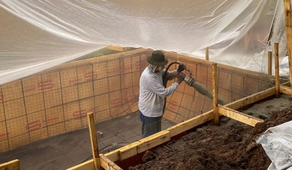 A construction worker spraying gunite on a swimming pool 