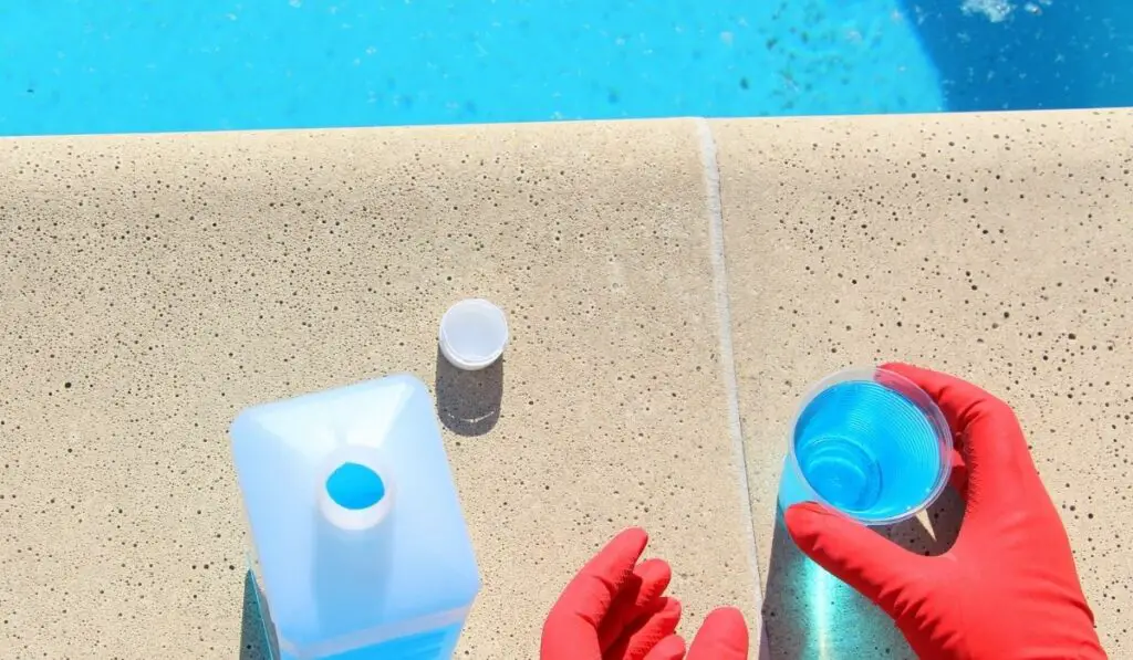 Blue liquid in a plastic glass for cleaning and clarity of water in swimming pools