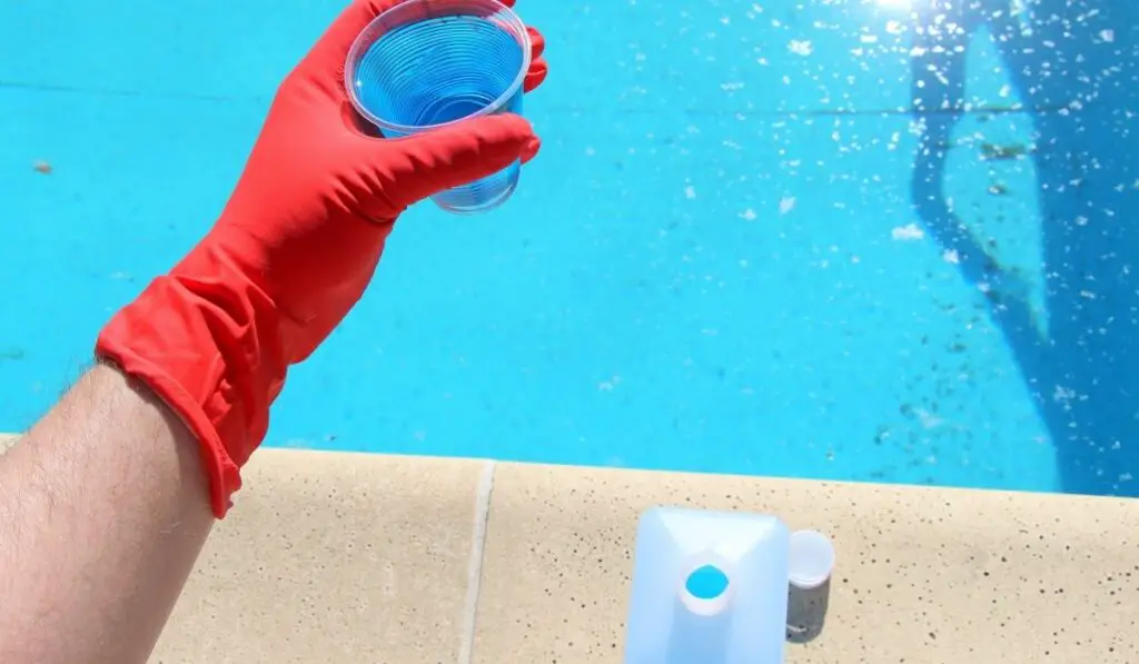 Blue liquid in a plastic glass for cleaning and clarity of water in swimming pools