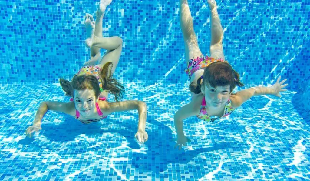 Happy smiling underwater children in swimming pool