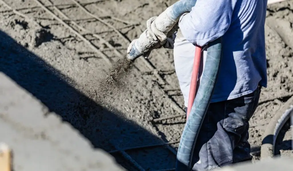 Pool Construction Worker Shooting Concrete, Shotcrete or Gunite Through Hose