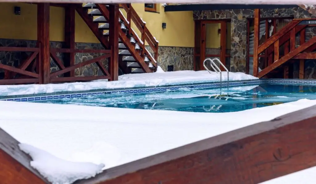 Swimming pool covered with snow near the cottage 