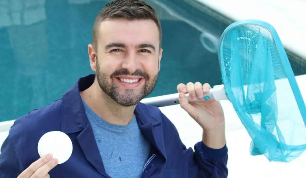 Worker using chlorine in swimming pool 