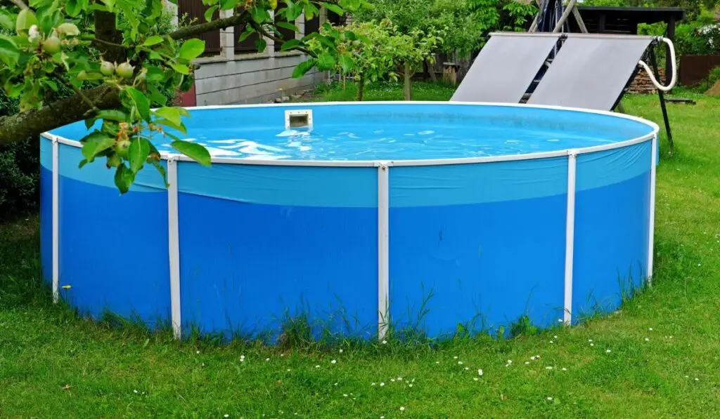Garden pool with black panels for water heating by the sun