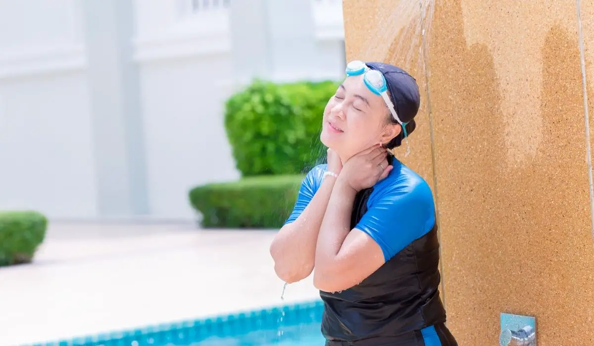 Woman adult in swimming suit water shower cleaning at hotel swimming pool
