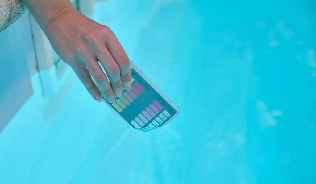 Woman hand filling ph and cl kit with pool water to test the quality