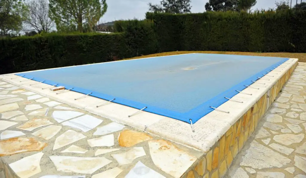 Swimming pool with a blue tarp for protection in winter