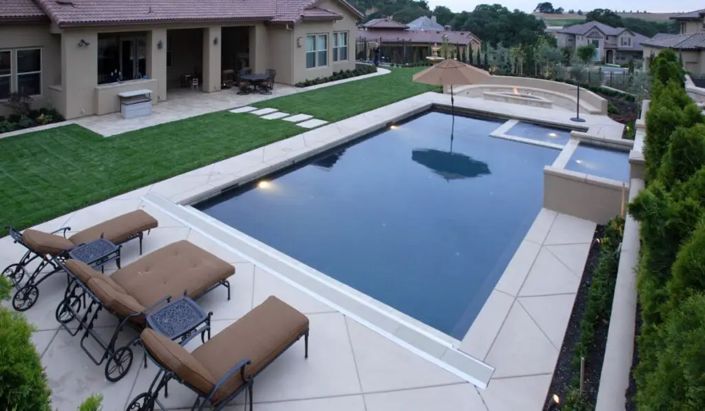 A pool with a waterfall in a luxury backyard 