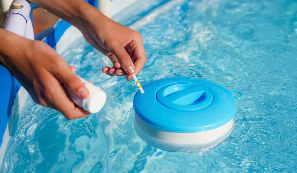 Checking the water quality of a pool with the help of a test strip with PH value 