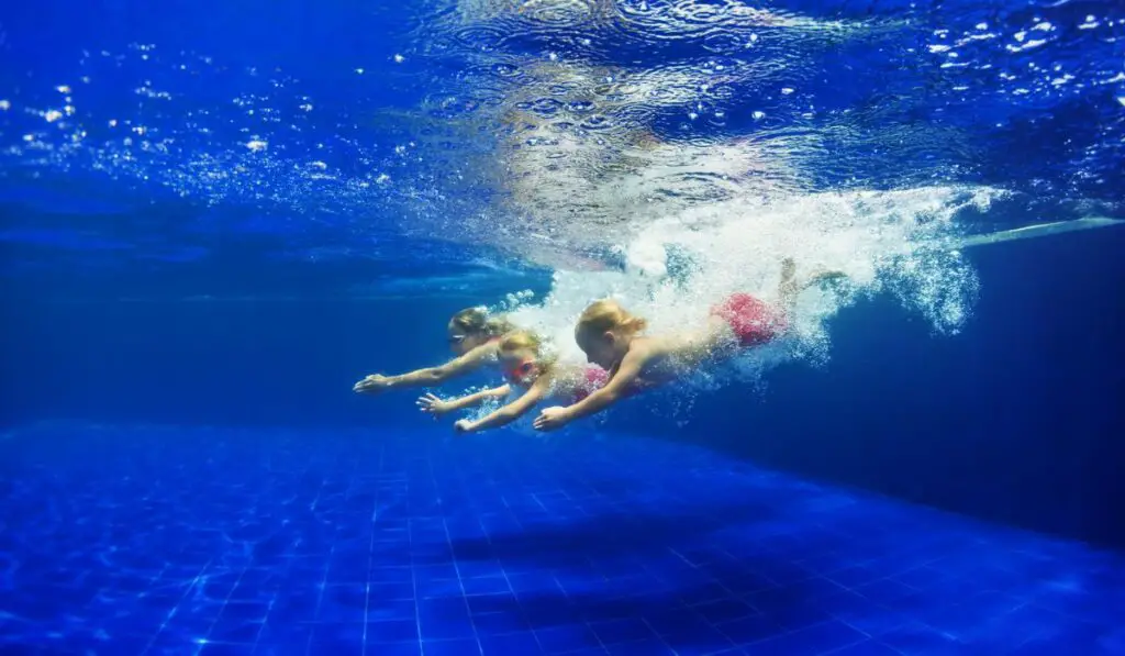 Kids with mother dive in swimming pool