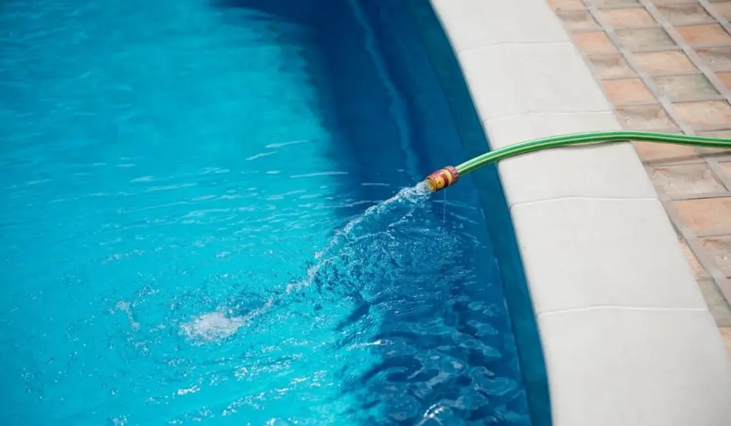 Water flowing from the hose into the pool 
