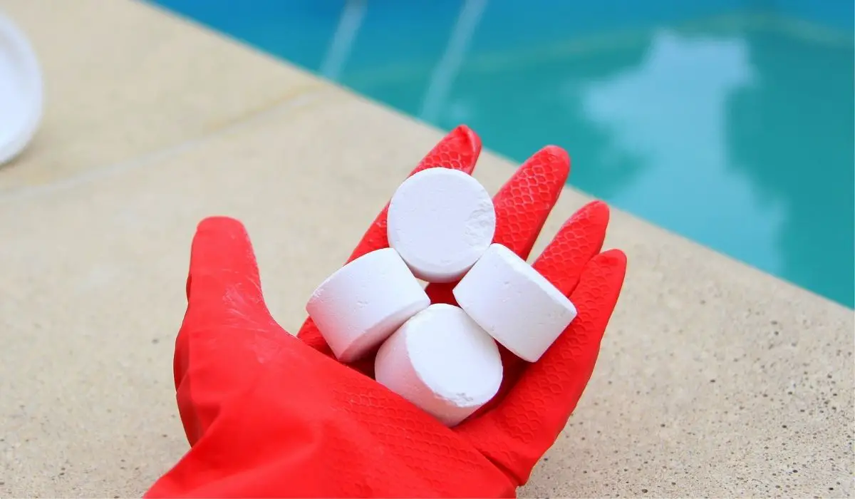 White mini-tablet of chlorine in the hand of the staff for disinfection of swimming pools