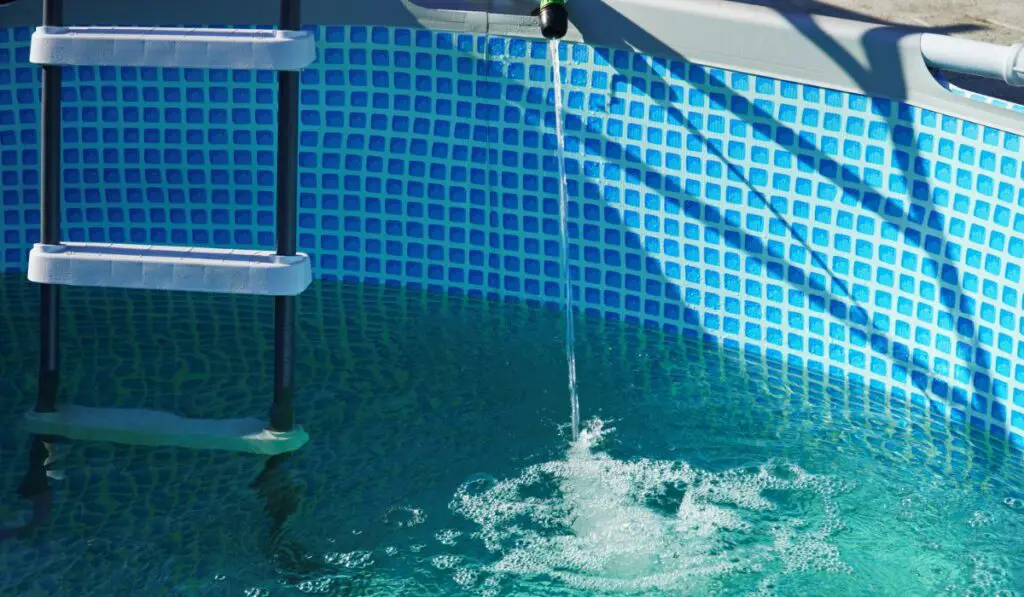 A Water pours from a hose into a small round pool