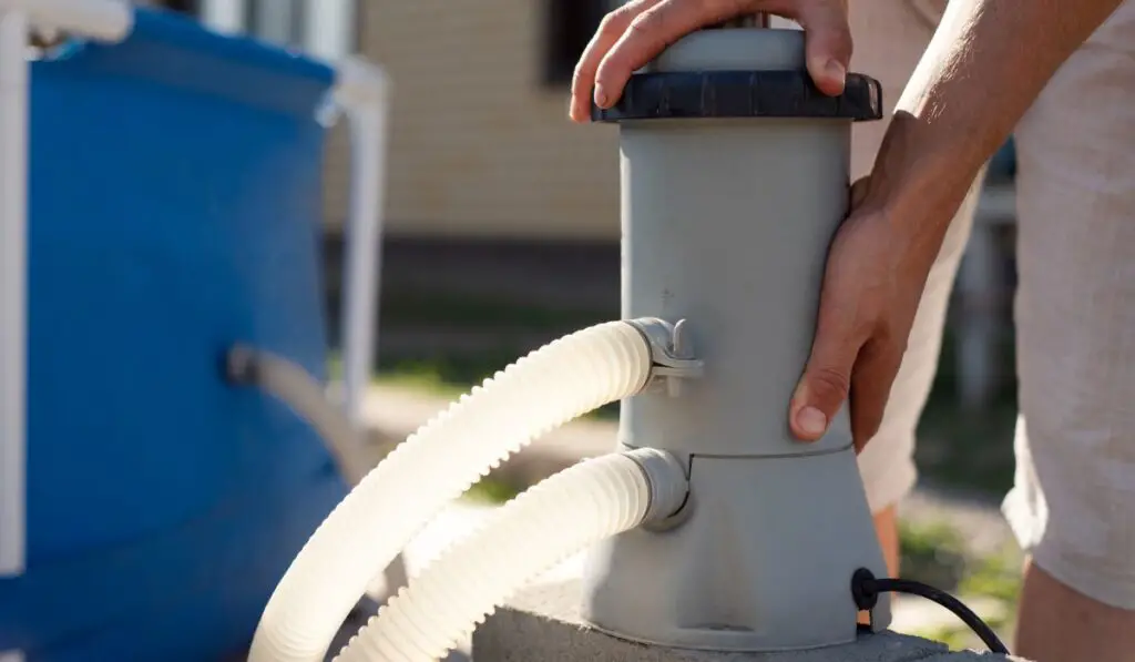 A man checks a filter for cleaning a home pool -