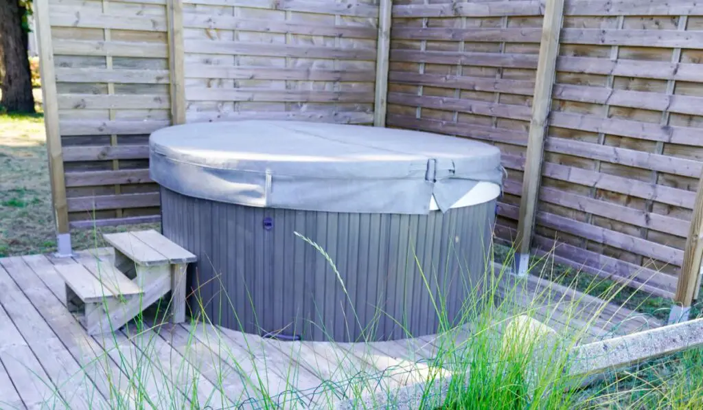 Hot Tub Spa with water bubbling and the lid in home wooden terrace garden house 