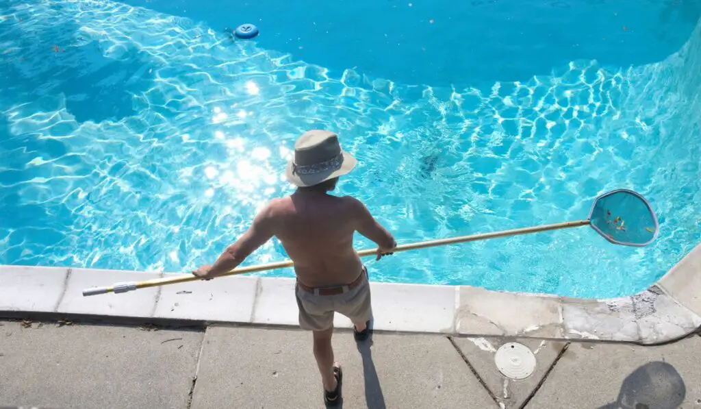 Man cleans swimming pool 