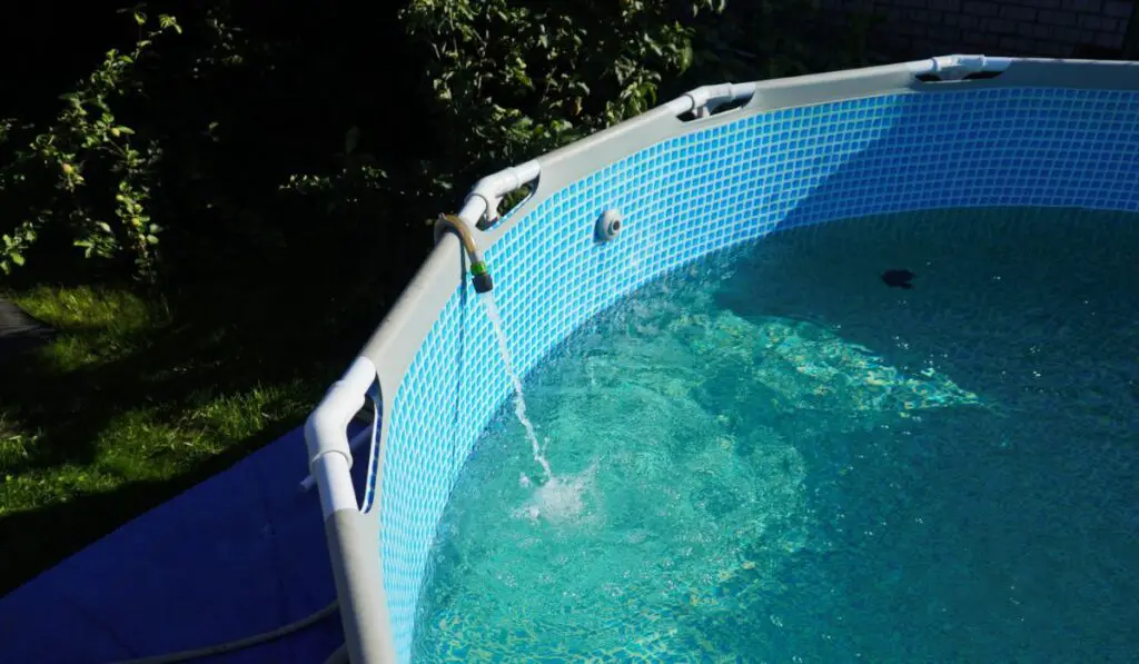 Water pours from a hose into a small round pool 