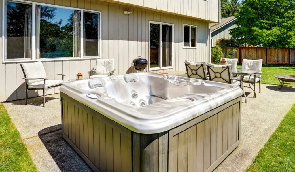 Backyard concrete floor patio area with hot tub