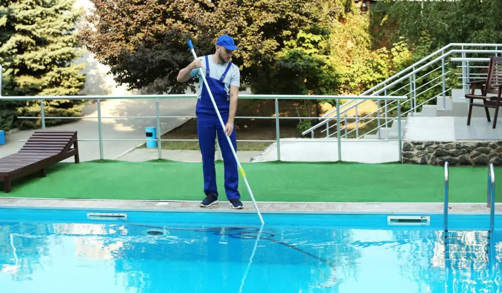 Male worker cleaning outdoor pool