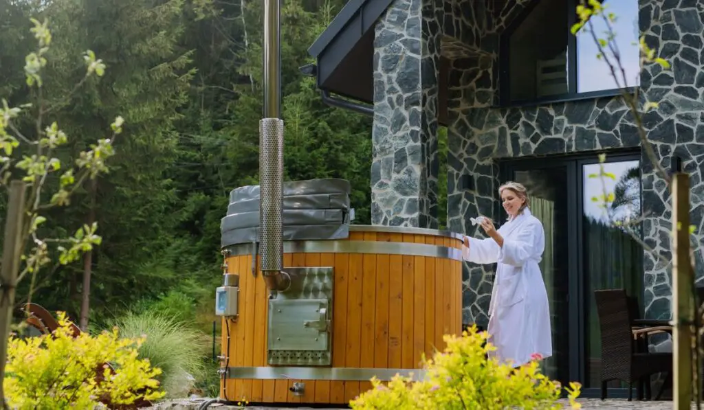 Young woman in bathrobe, checking temperature