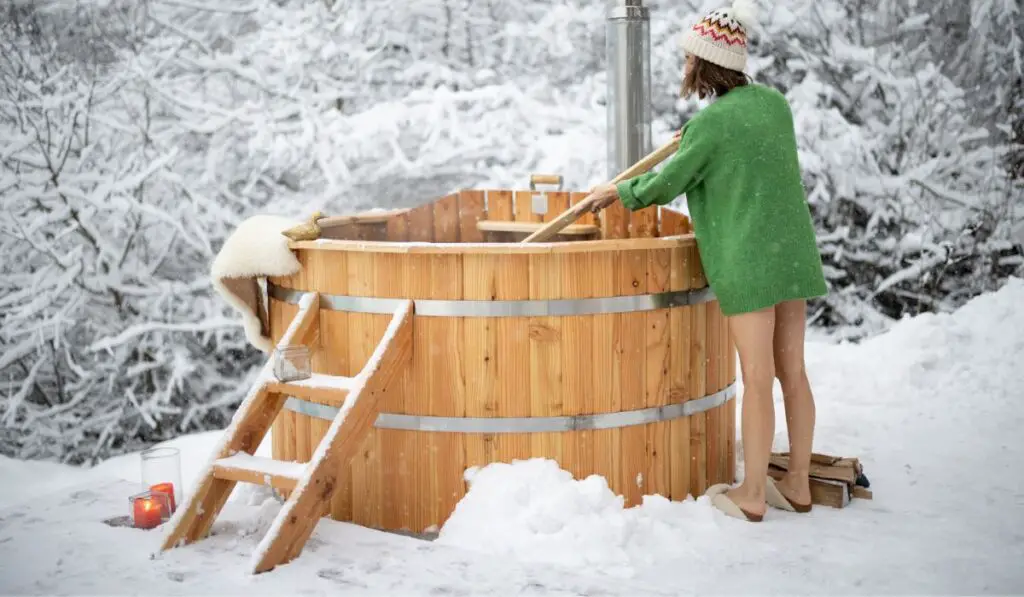 Woman mixing water before bathing in hot vat outdoors