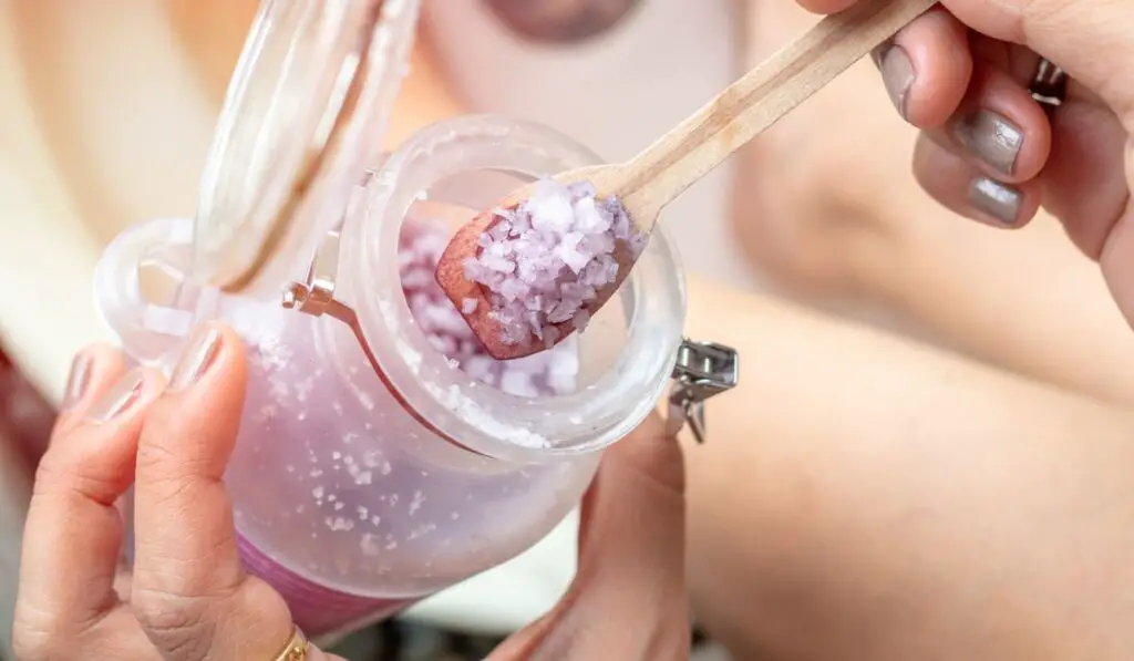 Hand scoop epsom salt with the small wooden spoon from salt bottle