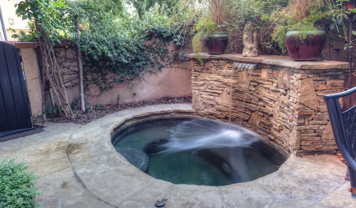 Oval hot tub spa with waterfall and feng shui garden decor