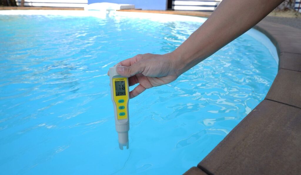 Digital water testing in female hand on swimming pool background