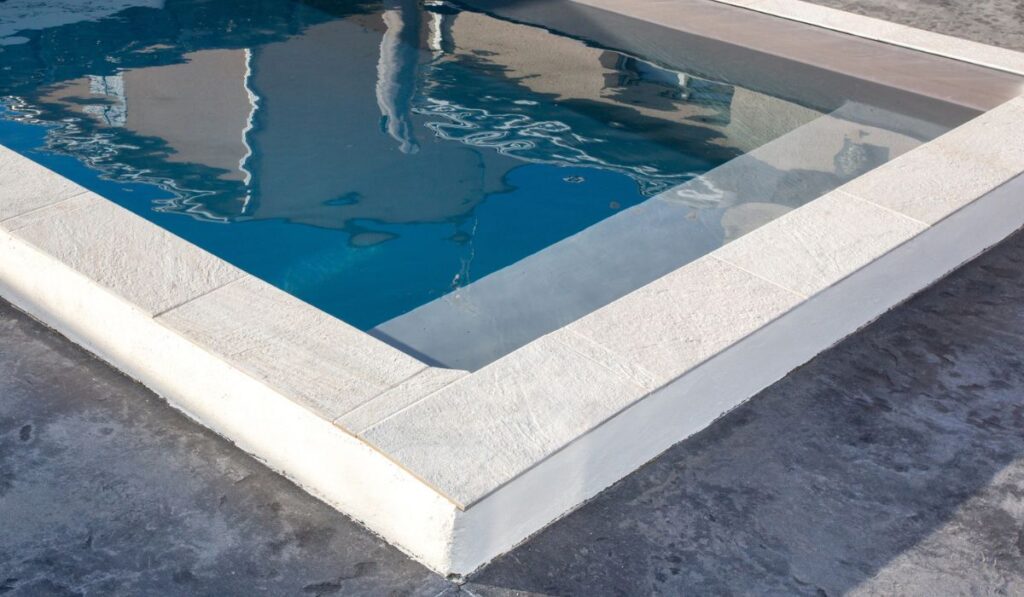 Home blue swimming pool with stone coping with a waxed concrete terrace house
