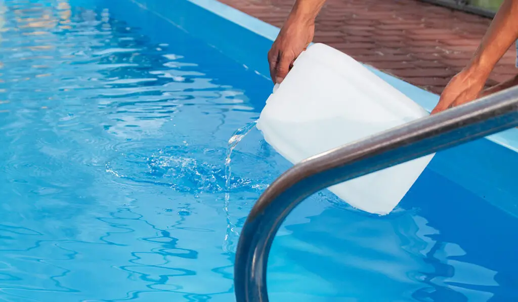 Man pouring chemicals into a pool